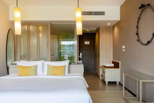 a bedroom with a large white bed with yellow pillows at The Sands Khao Lak by Katathani - SHA Extra Plus in Khao Lak