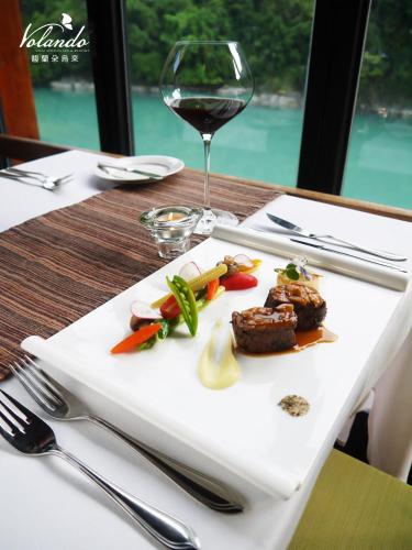 a plate of food on a table with a glass of wine at Volando Urai Spring Spa & Resort in Wulai