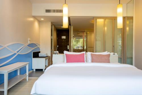 a bedroom with a large white bed with pink pillows at The Sands Khao Lak by Katathani - SHA Extra Plus in Khao Lak