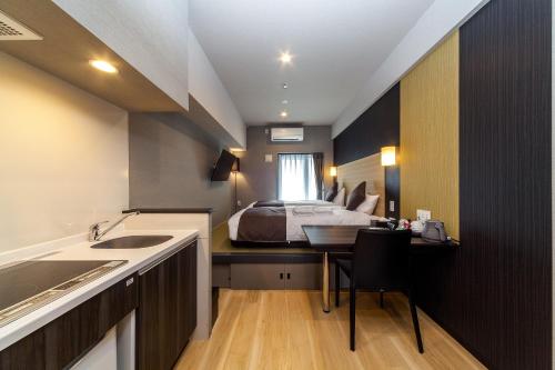 sypialnia z łóżkiem i biurkiem z umywalką w obiekcie HOTEL SUITE HIROSHIMA HAKUSHIMA w mieście Hiroszima