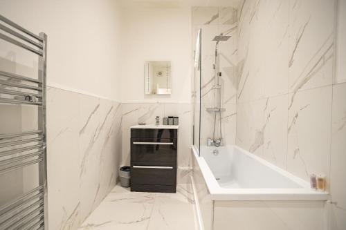 a white bathroom with a tub and a sink at Deluxe Modern 1&2 Bed Apartments Near Brighton Beach & Station in Brighton & Hove