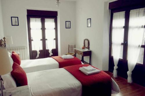 a bedroom with two beds with red and white sheets at La Casona De Tia Victoria in Rueda