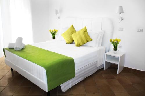Cama blanca con sábanas verdes y blancas y almohadas amarillas en Roma Resort Colosseum, en Roma