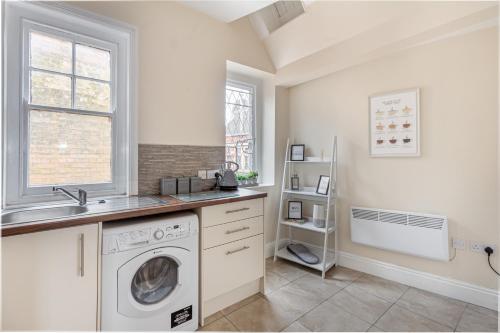 uma cozinha com uma máquina de lavar roupa e um lavatório em Guest Homes - Trinity Apartment em Worcester