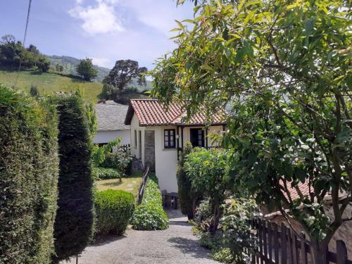 una pequeña casa blanca con una valla y arbustos en La casina de santulaya, en Cangas del Narcea