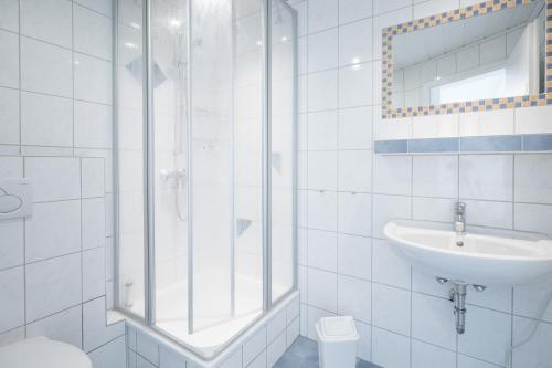 bagno bianco con doccia e lavandino di Bungalow Neuwarft, Wohnung 1 a Dagebüll