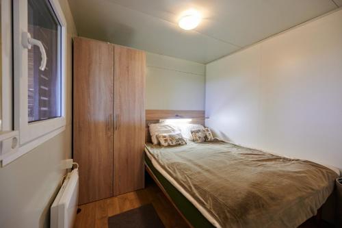 um pequeno quarto com uma cama e um armário de madeira em VINEA PANONIKA wine & mind retreat em Radenci