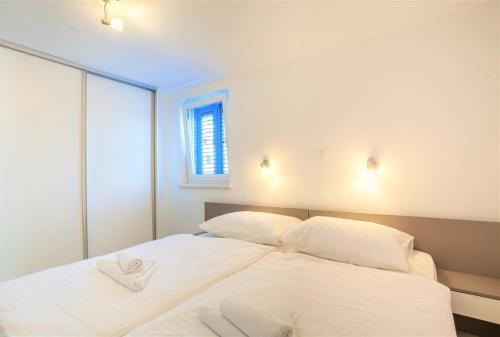 uma cama branca com duas almofadas brancas e uma janela em Best mediteranne Luxury em Cres