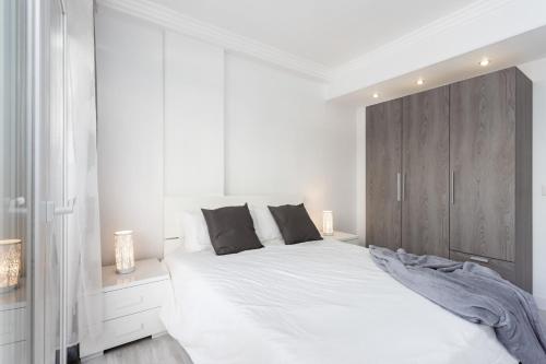 1 dormitorio blanco con 1 cama grande y armario de madera en Home2Book La Casita del Puerto, terrace & Pool, en Puerto de la Cruz