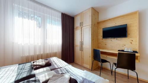 a bedroom with a bed and a desk and a television at Penzion Sabina in Vernár