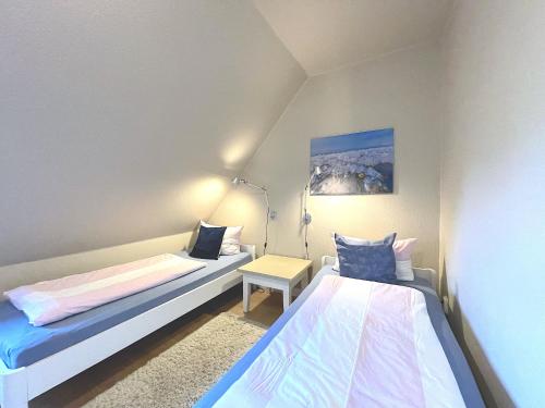 Dormitorio pequeño con 2 camas y lámpara en Haus Stübbe beim Dorfteich en Wenningstedt