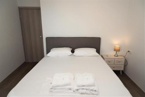 a bedroom with a white bed with two towels on it at Koules Sea View City Apartment in Heraklio