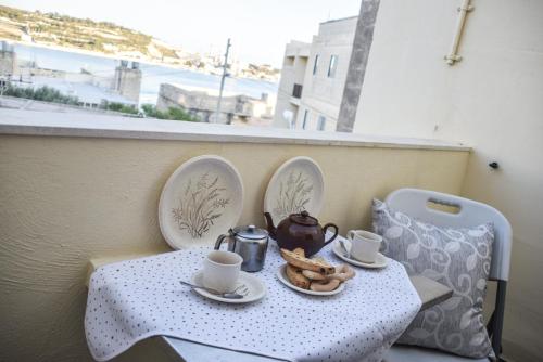 una mesa con tazas de té y galletas en el balcón en Mangion House, en Marsaxlokk