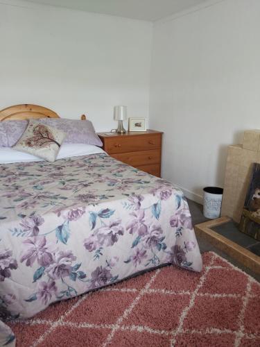 a bedroom with a bed with a floral bedspread and a rug at Self-catering Cottage at Benview in Staffin