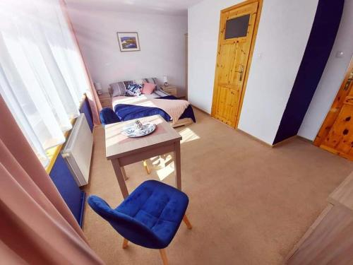 シフィエラドゥフ・ズドルイにあるPokoje gościnne "Trudziń-SKI"のテーブル、青い椅子、ベッドが備わる客室です。