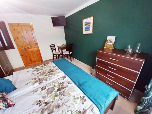 a bedroom with a bed and a dresser and a green wall at Pokoje gościnne "Trudziń-SKI" in Świeradów-Zdrój