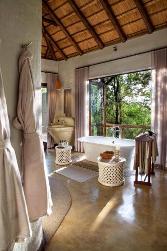 a bathroom with a tub and a large window at Madikwe Hills Private Game Lodge in Madikwe Game Reserve