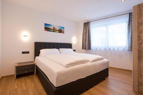 sypialnia z dużym łóżkiem i oknem w obiekcie Arlalps Apart w mieście Pettneu am Arlberg