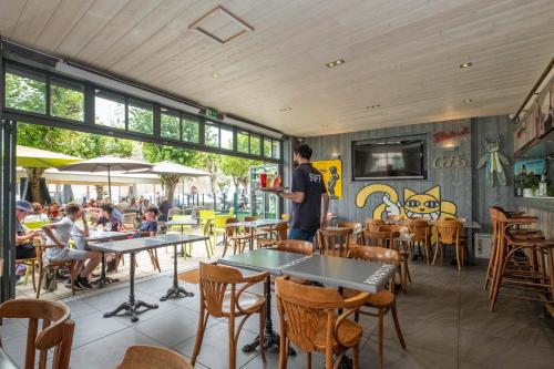 un homme debout dans un restaurant avec des tables et des chaises dans l'établissement Hotel Le Clocher, à Ars-en-Ré