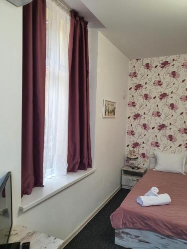 a bedroom with a bed and a window with red curtains at Guest House Gurkov in Veliko Tŭrnovo