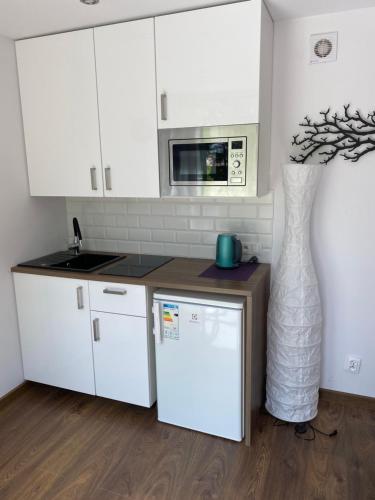 a kitchen with white cabinets and a vase at Koziula - Domki i Leśne SPA na Kaszubach in Przywidz