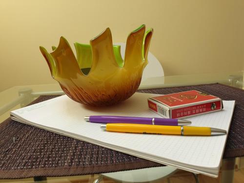 a desk with a book and a bowl and pens at Apartman Vid in Soko Banja