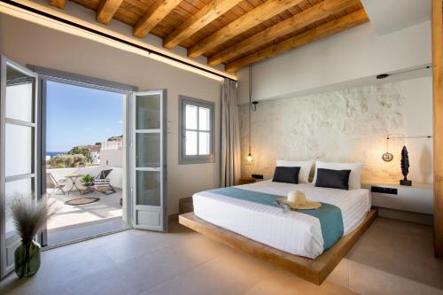 a bedroom with a large bed and a balcony at Lindos Serenity Suites in Líndos