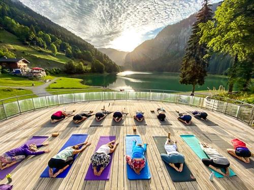 a group of people doing yoga on a deck next to a lake at Hotel Du Lac in Montriond