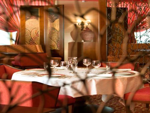 a table with wine glasses on it in a restaurant at Royal Hotel Oran - MGallery Collection in Oran