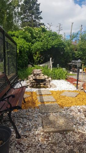 a park bench sitting on a stone walkway next to a garden at Joy Guesthouse in Siófok