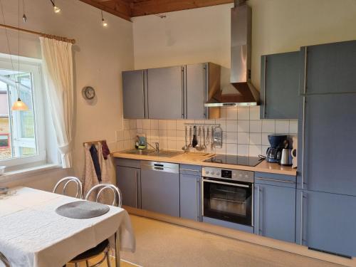 a kitchen with blue cabinets and a table and a table and a table at Appartements Erhol dich gut in Leutasch