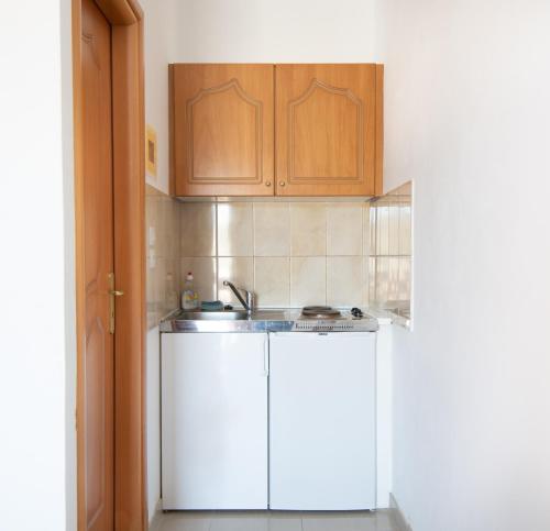 una cocina con armarios blancos y fregadero en Poros View, en Galatas