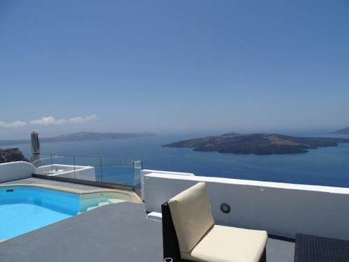 a balcony with a swimming pool and a chair at NEOKLASSIKO KOUKOULI in Fira