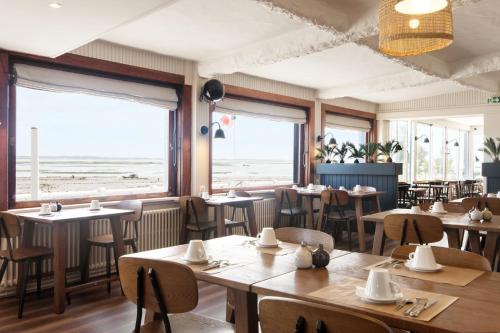 ein Restaurant mit Tischen und Stühlen und Blick auf den Strand in der Unterkunft Le Homard Bleu in Saint-Trojan-les-Bains