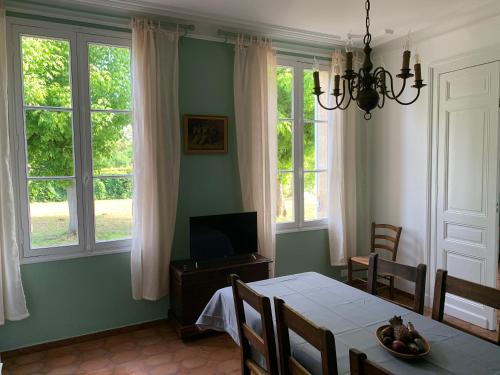 une salle à manger avec une table et deux fenêtres dans l'établissement Château Roseyrol proche Saint-Emilion, à Saint-Magne-de-Castillon