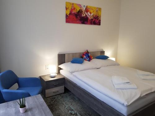 a bedroom with a bed and a blue chair at Penzion Vila Tereza in Hranice