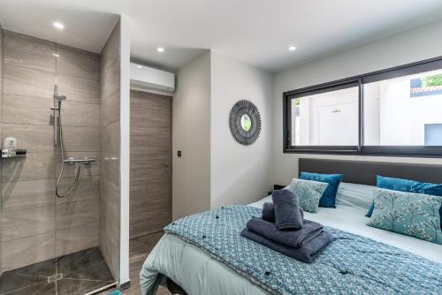 - une chambre avec une douche et un lit avec des oreillers bleus dans l'établissement Les Jardins de la Palmeraie - Sublime vue sur la baie dAjaccio, à Porticcio