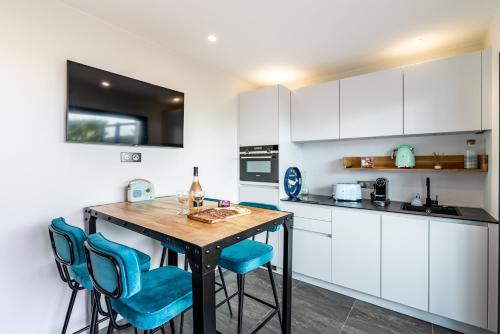 une cuisine avec une table en bois et des chaises bleues dans l'établissement Les Jardins de la Palmeraie - Sublime vue sur la baie dAjaccio, à Porticcio