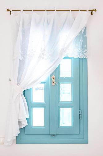 a window with a blue door and a curtain at THE SHIP in Lefkos Karpathou