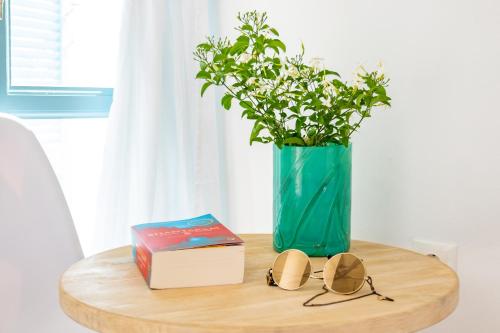 a table with a vase and a book and glasses at THE SHIP in Lefkos Karpathou