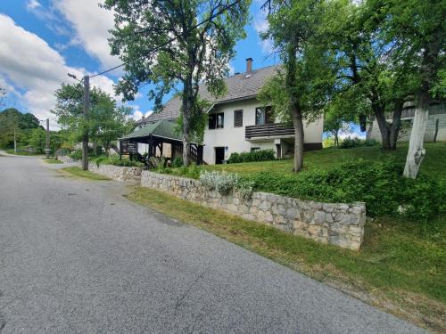 una casa blanca con una pared de piedra junto a una calle en Guest House Štefanija en Poljanak