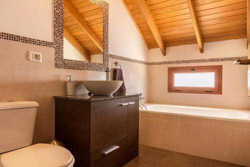 a bathroom with a toilet and a sink and a tub at Casa La Huertecilla in La Sorrueda