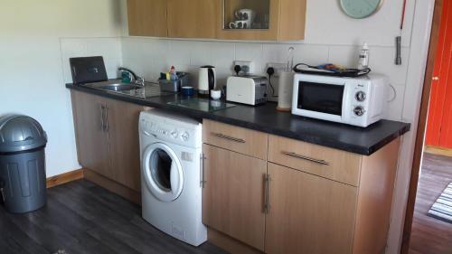a kitchen with a counter with a microwave and a dishwasher at Self-catering Cottage at Benview in Staffin