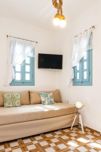 a living room with a couch and two windows at THE SHIP in Lefkos Karpathou