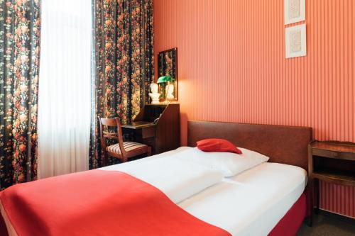 Dormitorio rojo con cama y escritorio en Das Kleine Hotel in ruhiger Stadtlage, en Wiesbaden