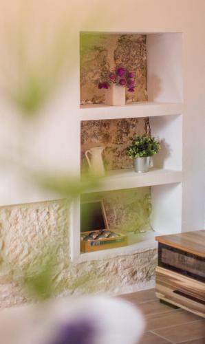 a wall with shelves with plants and pictures on it at Casa Pescador in Komiža