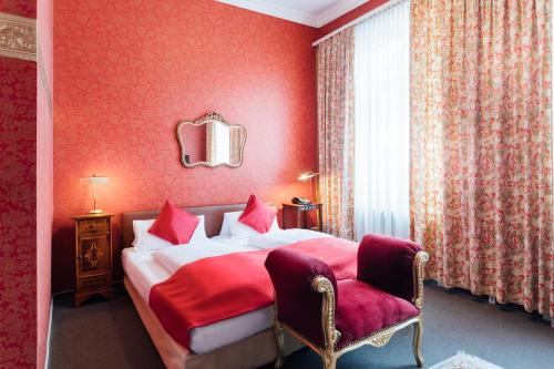 ein rotes Schlafzimmer mit einem Bett und einem Stuhl in der Unterkunft Das Kleine Hotel in ruhiger Stadtlage in Wiesbaden