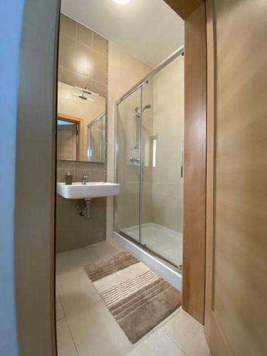 a bathroom with a glass shower and a sink at Hepburn Holiday Apartment in Birżebbuġa