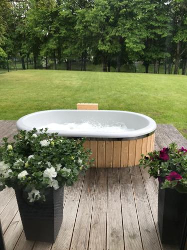 a bath tub sitting on a wooden deck with flowers at Mazoji vila in Birštonas