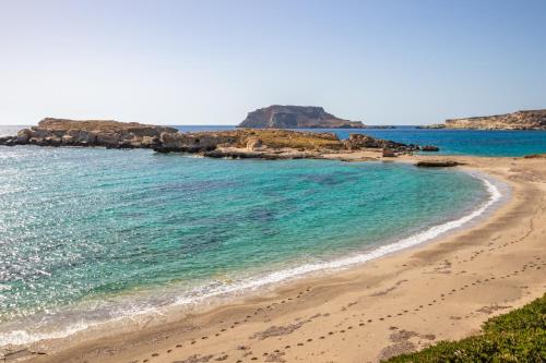 a beach with turquoise water and rocks in the background at THE SHIP in Lefkos Karpathou